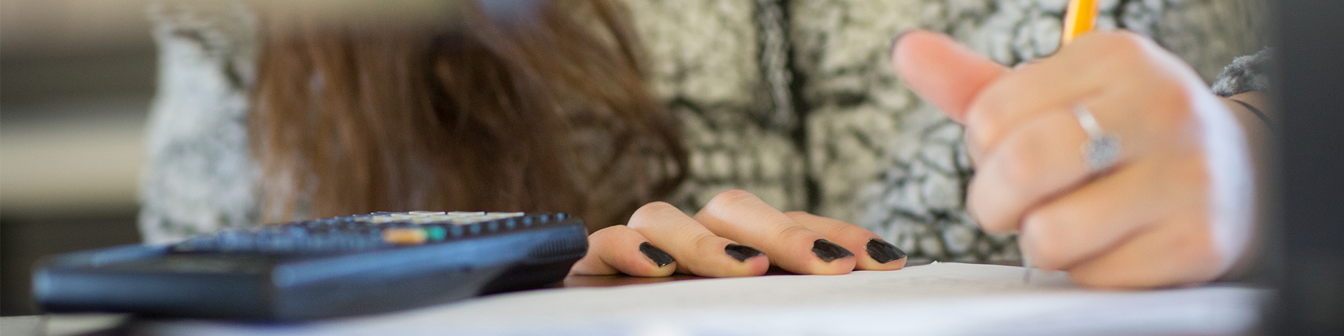 A hand holds a pencil and writes on a piece of paper