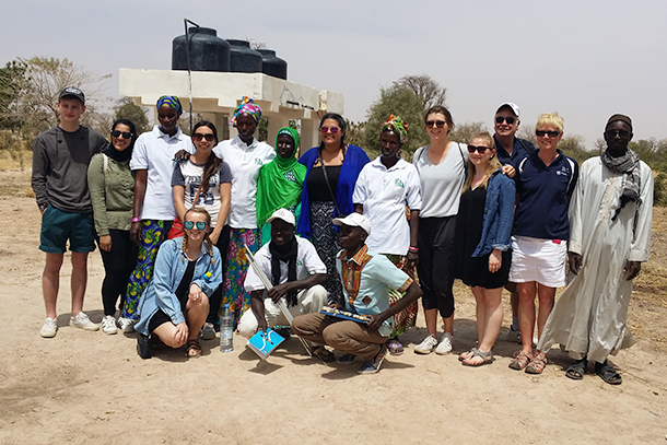 Students standing at farm with Senegalese farmers