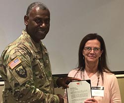 A man presents a woman with a document and shakes her hand